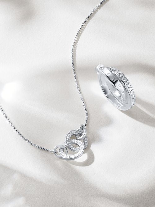 Eine silberne Kette und ein silberner Ring auf weißem Untergrund