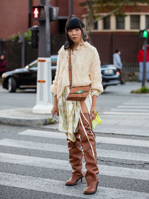 Susie Bubble in braunen slouchy Overknees zu einem seidigen Rock und einen cremefarbenen Strickpullover.