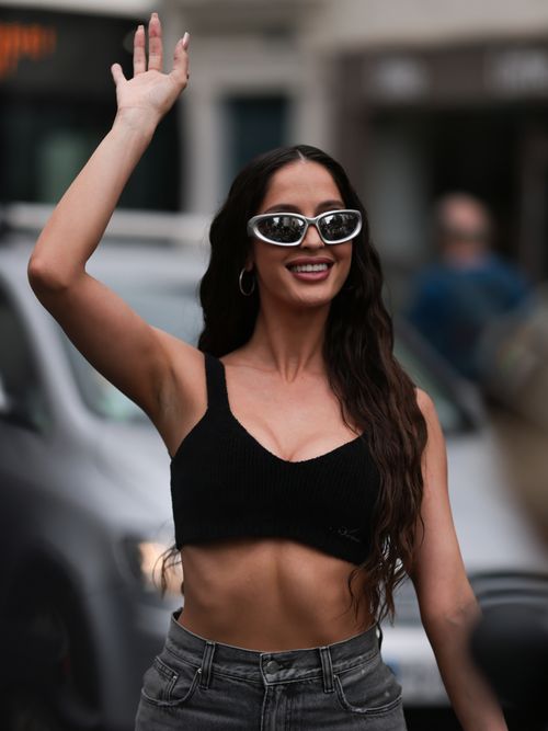 A Fashion Week guest is wearing grey sunglasses from Balenciaga, silver earrings/hoops, a black cropped top, a grey pair of trousers with large pockets and a black bag from Amiri with a bandana wrapped around the handle outside Amiri Show during the Menswear Spring/Summer 2024 as part of Paris Fashion Week on June 22, 2023 in Paris, France.