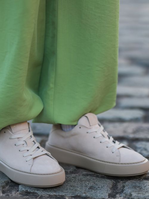 Close up von beigen Sneakers und einer grünen Hose.