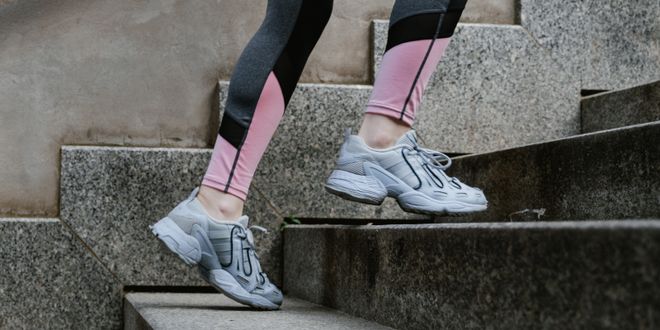 Frau läuft eine Stiege rauf in Sportkleidung und mit Laufschuhen