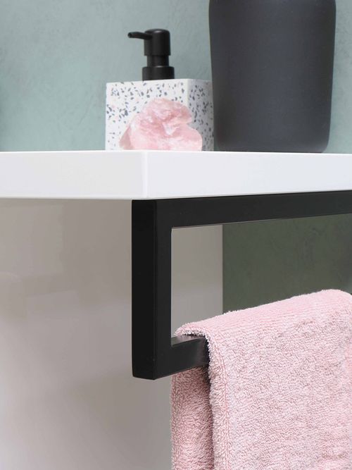 Ein Terrazzo-Seifenstpender, der am Waschbecken steht und unten hängt ein rosa Handtuch.