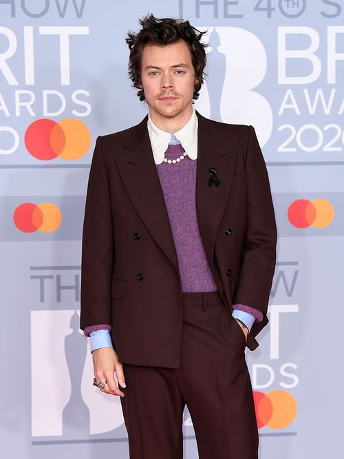 Harry Styles mit braunem Anzug, Rüschenkragen und Perlenkette.