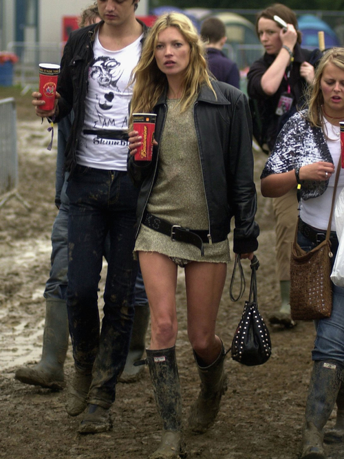 Kate Moss at the 2005 Glastonbury Festival wearing a long sweater, black leather jacket, and Hunter boots