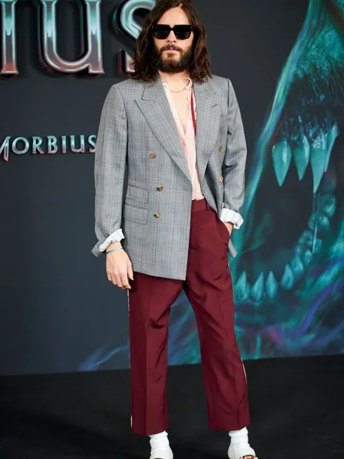 Jared Leto auf der Premiere von Morbius mit einem grauen Sakko, rosafarbenen Hemd und roter Hose, mit Sonnenbrille.