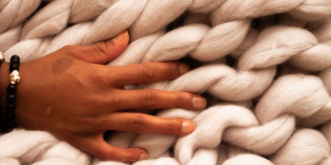 Makroaufnahme von einer Hand in grober Strickwolle