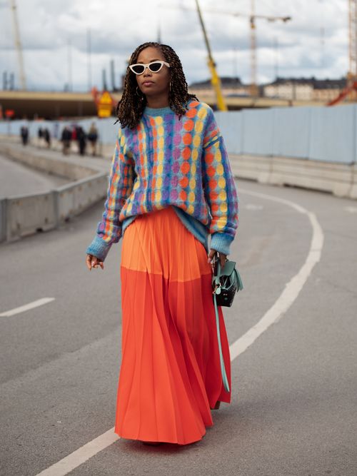 Content Creator Elizabeth Delphine kombiniert den herbstlichen Strickpullover zum sommerlichen Maxirock auf der Stockholm Fashion Week