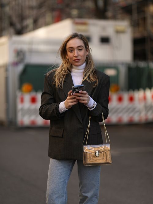 Sonia Lyson in einem dunklen Blazer zur Jeans und einen weißen Rollkragen-Pullover.