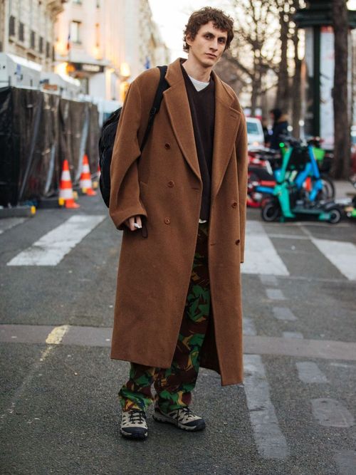Model und Künstler Henry Kitcher trägt einen braunen oversized Mantel mit Camouflage Hose und Hiking Boots auf der Milan Fashion Week