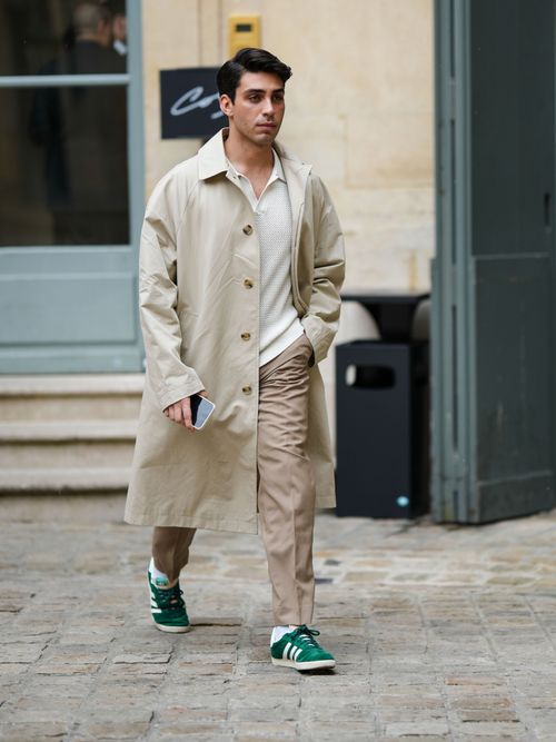 Street Style Look aus Paris, wo ein Influenzier einen Trenchcoat mit weißen T-Shirt, beiger Chinohose und Sneaker trägt.