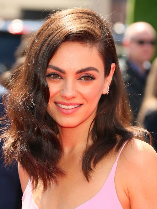 Mila Kunis trägt einen Seitenscheitel und Locken