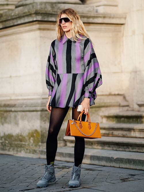 Veronika Heilbrunner mit einem Lila gstreiften Overall zu einer organgenen Tasche.