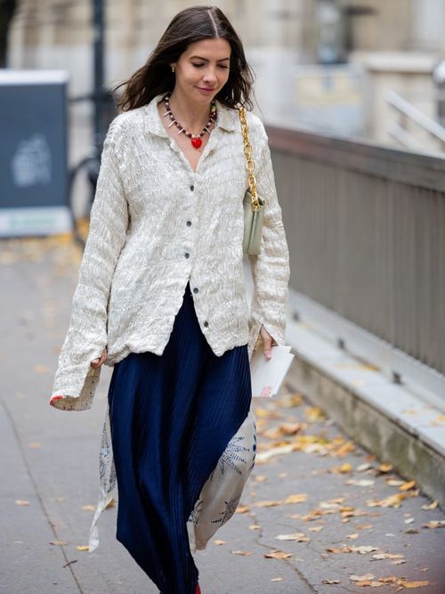 Street Style Look wo die Frau eine Bluse mit Knitterfalten und Rock auf der Paris Fashion Week trägt.