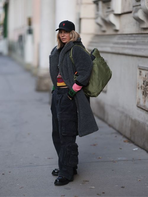 Influencerin Karin Teigl trägt einen Teddy Mantel in grau mit einem bunten Pullover und schwarzer Cargo Hose in Wien