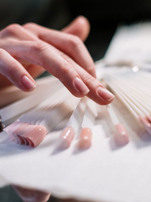 Frauenhände, die über eine Farbpalette an Nagellackfarben streichen.