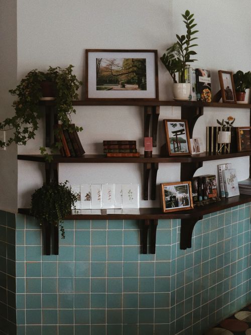 Wand mit Regalen, wo Bücher drapiert sind.