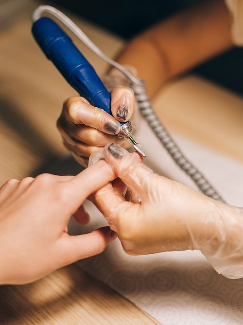 Hände mit Handschuhen, die an anderen Händen feilen.