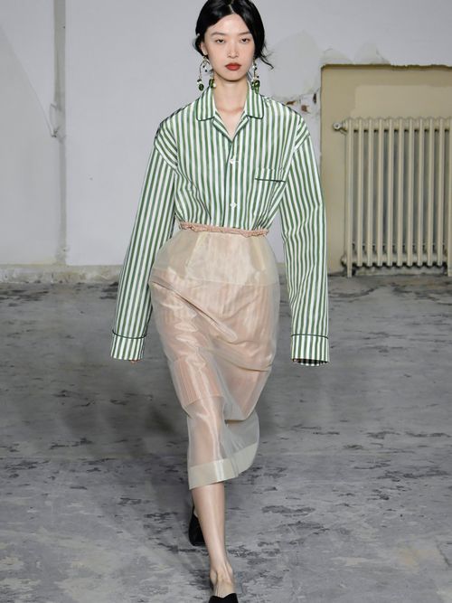 Runway Look von der Carven Fashion Week, wo das Model eine gestreifte Bluse, einen Bleistiftrock, Ballerinas und Statement-Ohrringe trägt.
