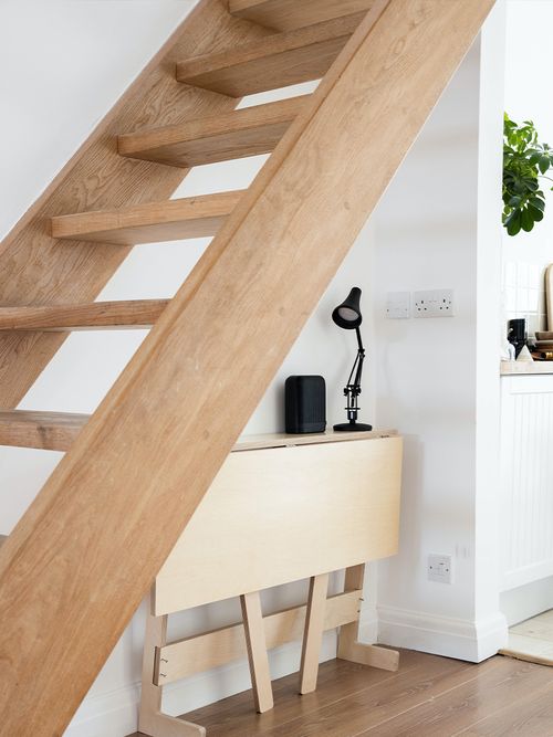 Ein klappbarer Schreibtisch unter einer Holztreppe.