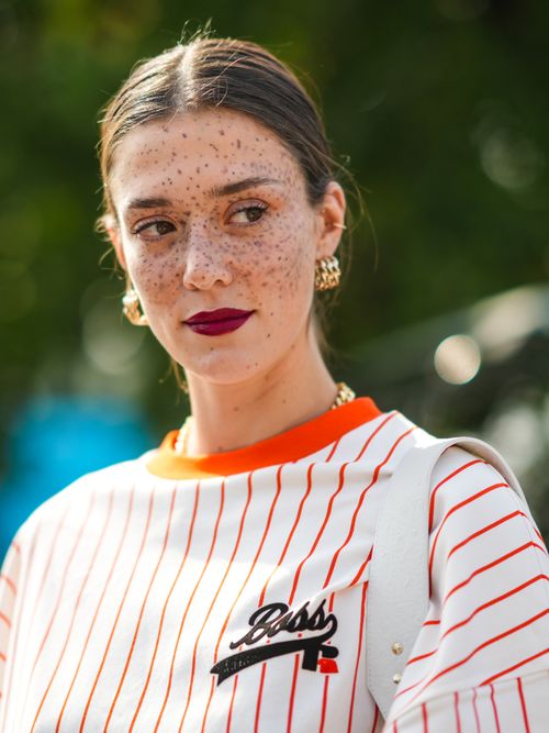 Model Maeva Marshall trägt ein gestreiftes Baseball-T-Shirt mit goldenen Ohrringen auf der Milan Fashion Week.