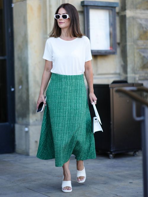 Street Style Look von der Copenhagen Fashion Week, wo ein Gast einen Midirock in Grün mit einem weißem T-Shirt trägt.