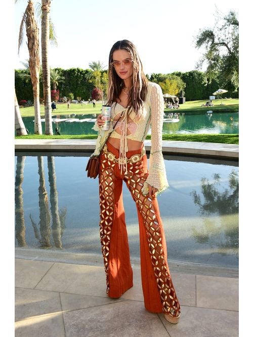 Alessandra Ambrosio wears orange sunglasses, a white cut-out blouse, bedazzled orange trousers.