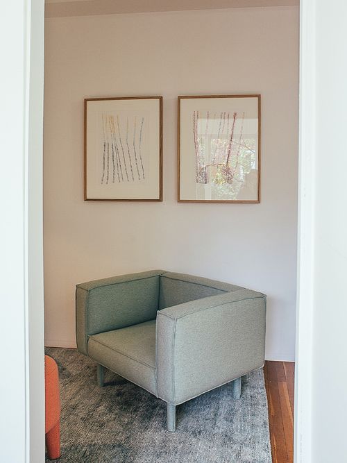 Grauer moderner Sofasessel vor einer Wand mit zwei Bildern.