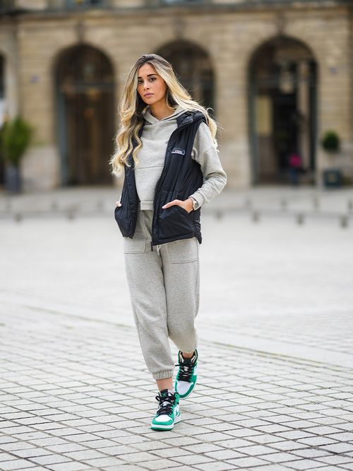 Streetstyle mit einem grauen Jogginganzug und einer schwarzen Weste zu grün-weißen Sneakers.