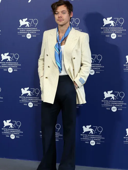 Harry Style bei einer Premiere in Los Angeles und trägt ein weißes Sakko mit T-Shirt und Halstuch sowie einer schwarzen Hose.