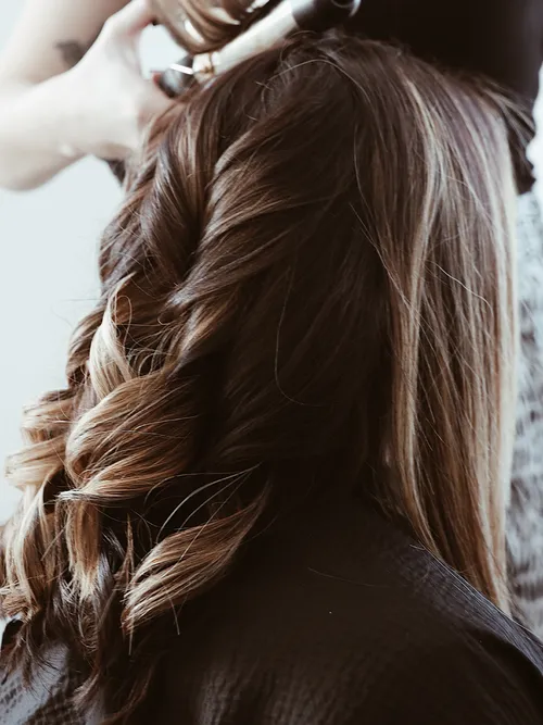 Braune Haare die zur Hälfte schon mit einem Lockenstab gewellt wurden.