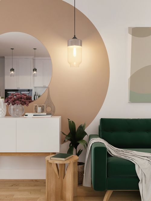 Interiorfoto von einem Wohnzimmer mit einer grünen Couch, Decke, Beistelltisch einer Kommode mit rundem Spiegel.