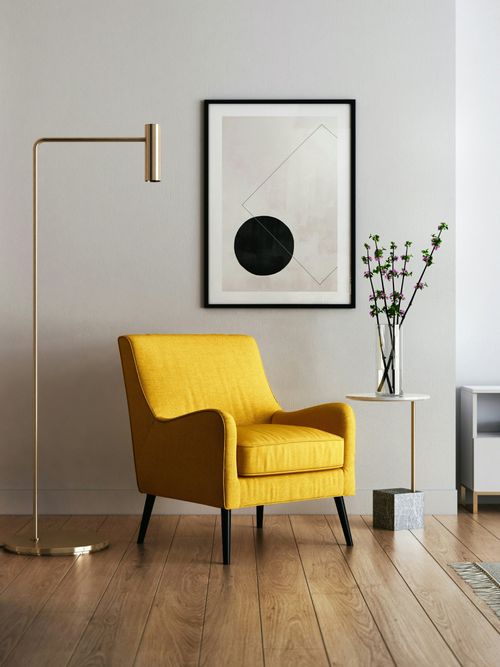 Foto von einem Loungebereich, mit einem gelben Sessel, abstrakten Beistelltisch, Blumen und Bild mit grafischem Druck.