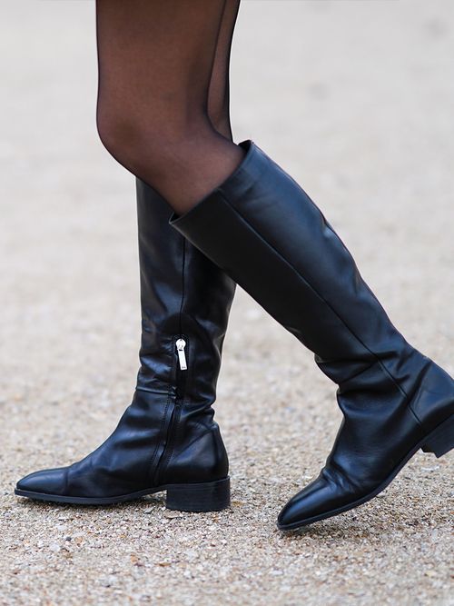 Close up von kniehohen schwarzen Stiefeln zu einer semitransparenten Strumpfhose.