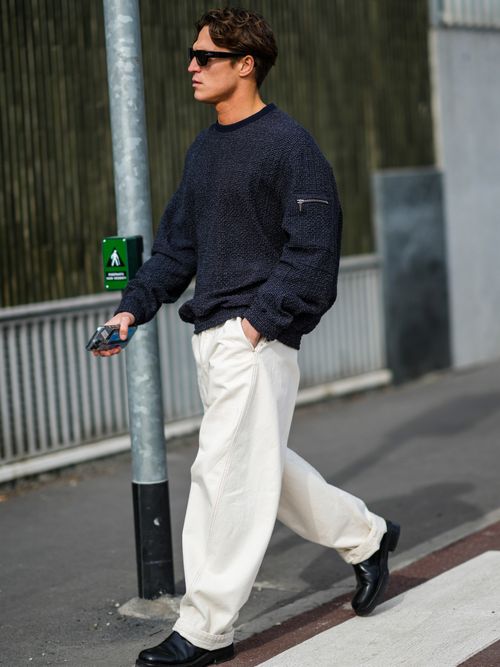 Ein Mann trägt einen Oversized-Pulli mit Sonnenbrille und einer weit geschnittenen White-Denim auf der Milan Fashion Week