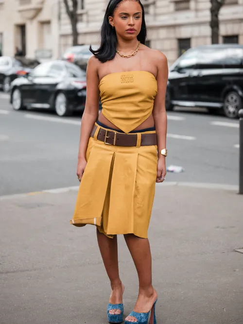 Paola Locatelli wears yellow Miu Miu sleeveless top, matching skirt, brown belt, denim platform sandals, outside Miu Miu, during the Womenswear Fall/Winter 2024/2025 as part of Paris Fashion Week on March 05, 2024 in Paris, France.