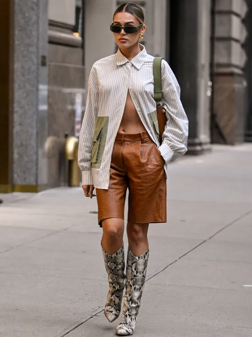 Natalie Zarra is seen wearing a striped pocket shirt, brown leather shorts and snakeskin boots outside the Khaite show during NYFW Spring/Summer 2025 on September 07, 2024 in New York City.