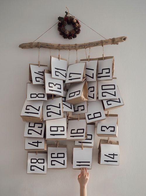 Ein Adventskalender an einem Ast mit Papiertüten.