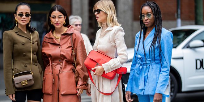 Xenia Adonts in einem weißen Outfit mit roter Tasche steht neben weitern Influencerinnen.