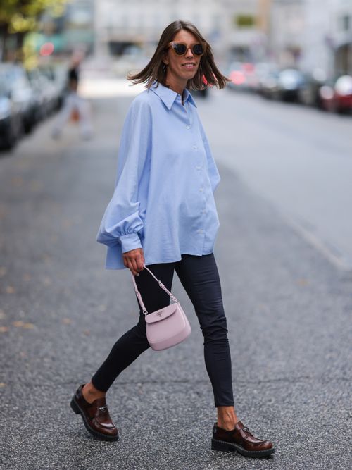 Katrin Lehbruner trägt eine hellblaue Bluse, Jeansleggings, Loafer und rosa Tasche in Hamburg.