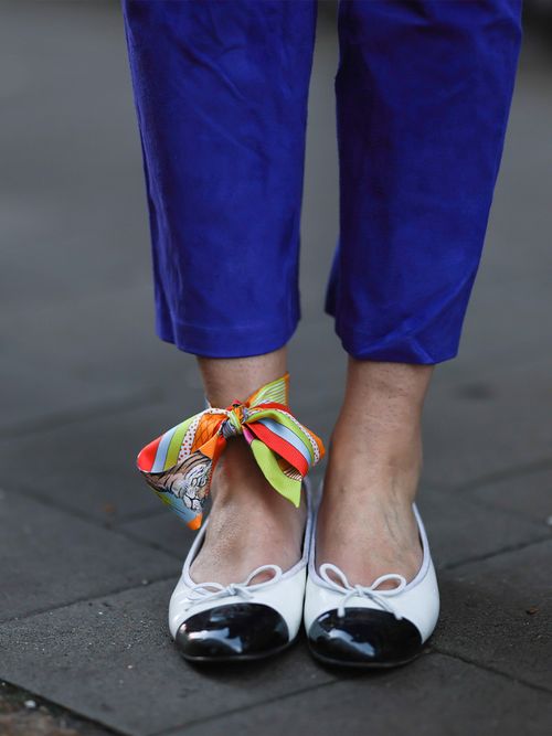 Close up von schwarz/weißen Ballerinas und einem Seidentuch am Fußgelenk.