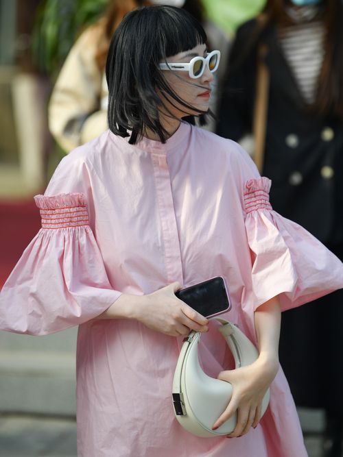 Street Style Look von einem Gast der ein rosa Blusenkleid mit weißer Sonnenbrille und weißer Handtasche in Beijing trägt.
