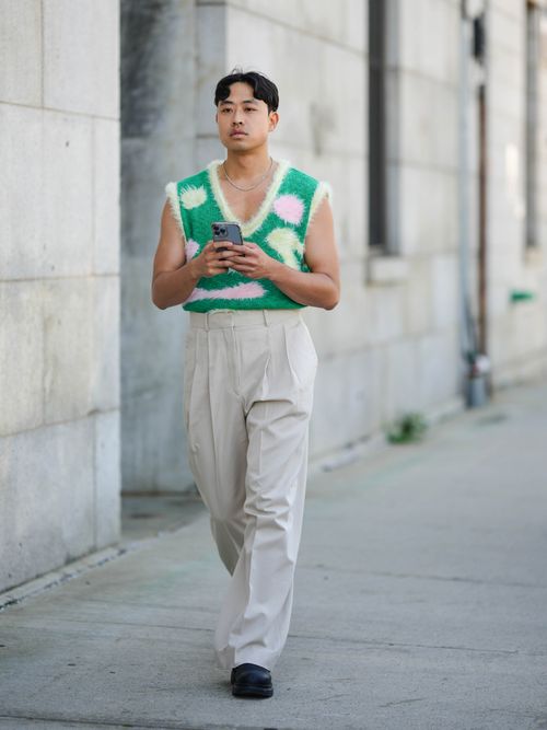 Street Style Look von der New York Fashion Week, wo ein Gast einen bunten Pullunder mit einer Bundfaltenhose trägt.