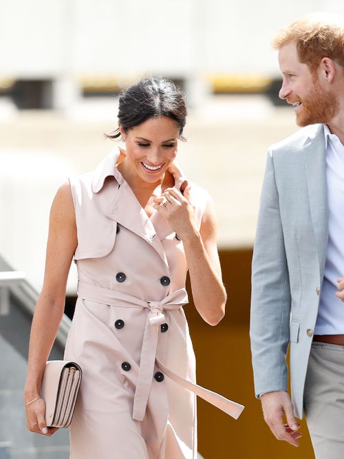 Meghan Markle in einem ärmellosen Trenchcoatkleid an der Seite von Prinz Harry.