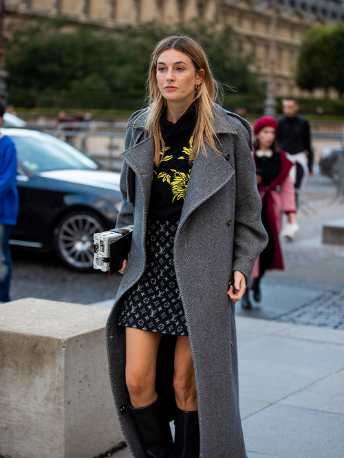 Camille Charriere in einem grauen Mantel und einem Minirock von Louis Vuitton.