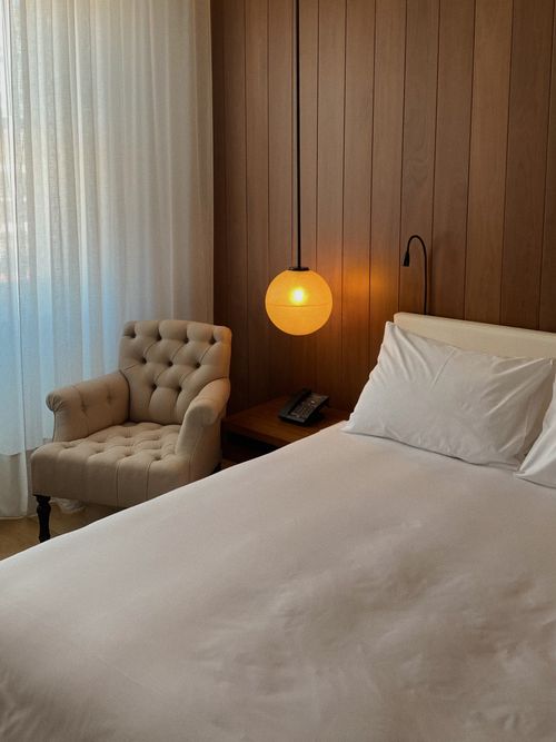 Foto von einem Hotelschlafzimmer mit runder Lampe und einem Sofa-Stuhl.