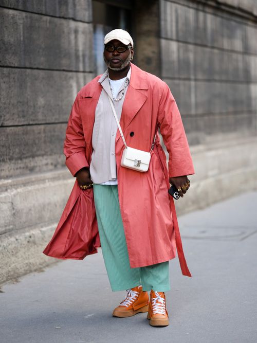 Street Style Look auf der Paris Fashion Week wo ein Mann einen pinken Trenchcoat für den Herbst trägt