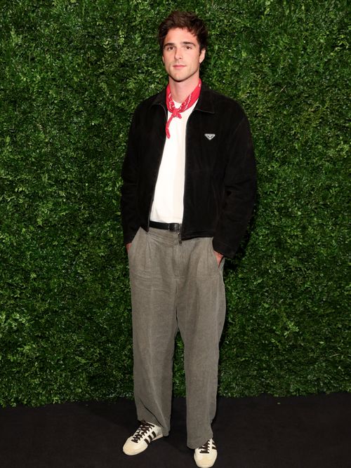 Jacob Elordi trägt einen schwarzen Cardigan, weißes T-Shirt mit rotem Bandana und eine braune Hose in London.