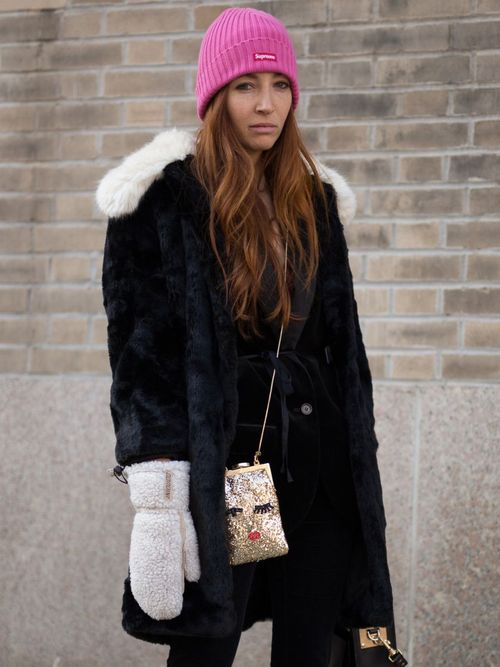 Sarah Slutsky trägt einen schwarzen Mantel aus Fell mit einem schwarzem Kleid und weiße Handschuhe aus Fell in New York City