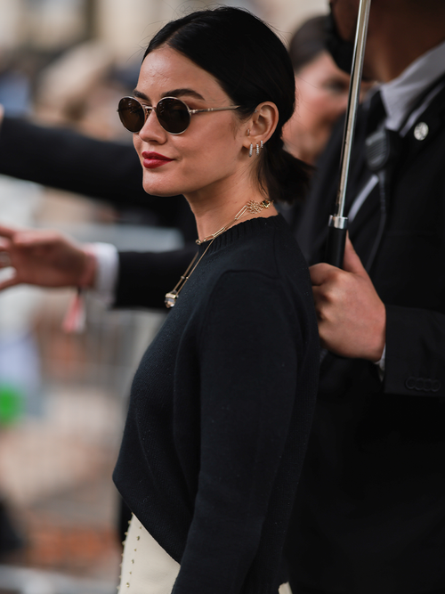 Lucy Hale mit einem schwarzen Oberteil und einer runden Sonnenbrille.