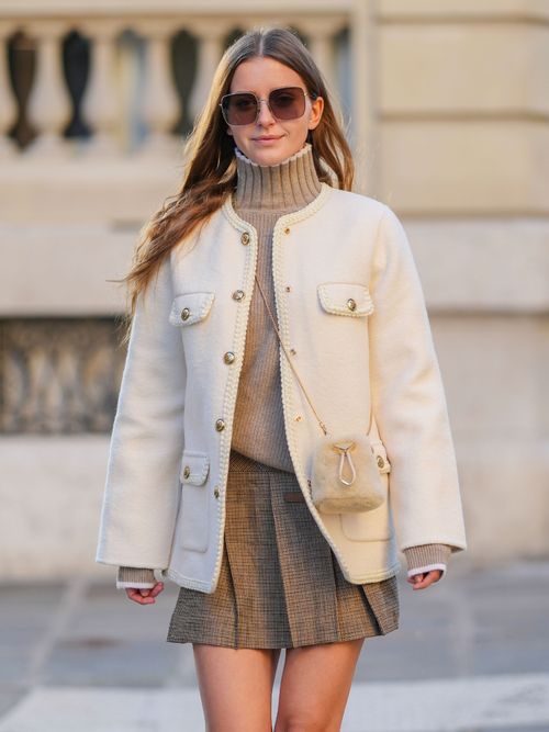 Diane Batoukina trägt eine weiße Jacke, beigen Rollkragen und karierten Faltenrock in Paris.